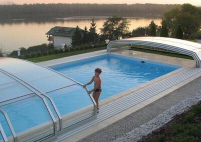 Swimming pool enclosure with retractable cover